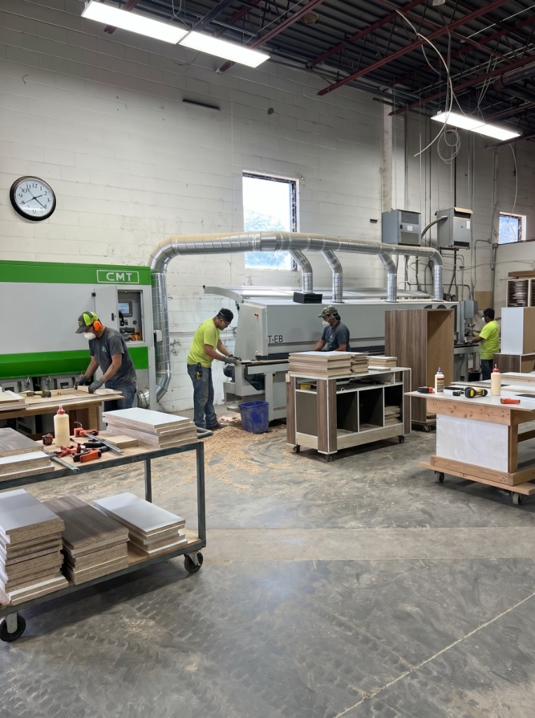 Craftsmen assembling cabinetry on the Dream House Improvement factory floor
